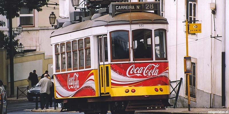 Een trammetje van lijn 28 schuifelt door de steile en bochtige straatjes van de Alfama wijk in Lissabon