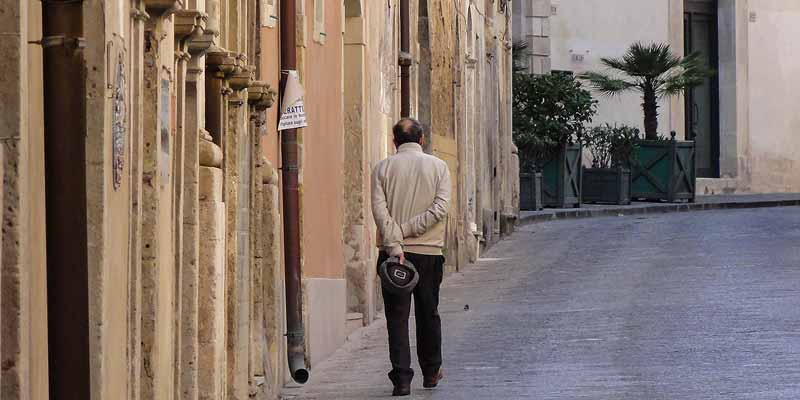 Een oud mannetje wandelt door de straten van Palermo
